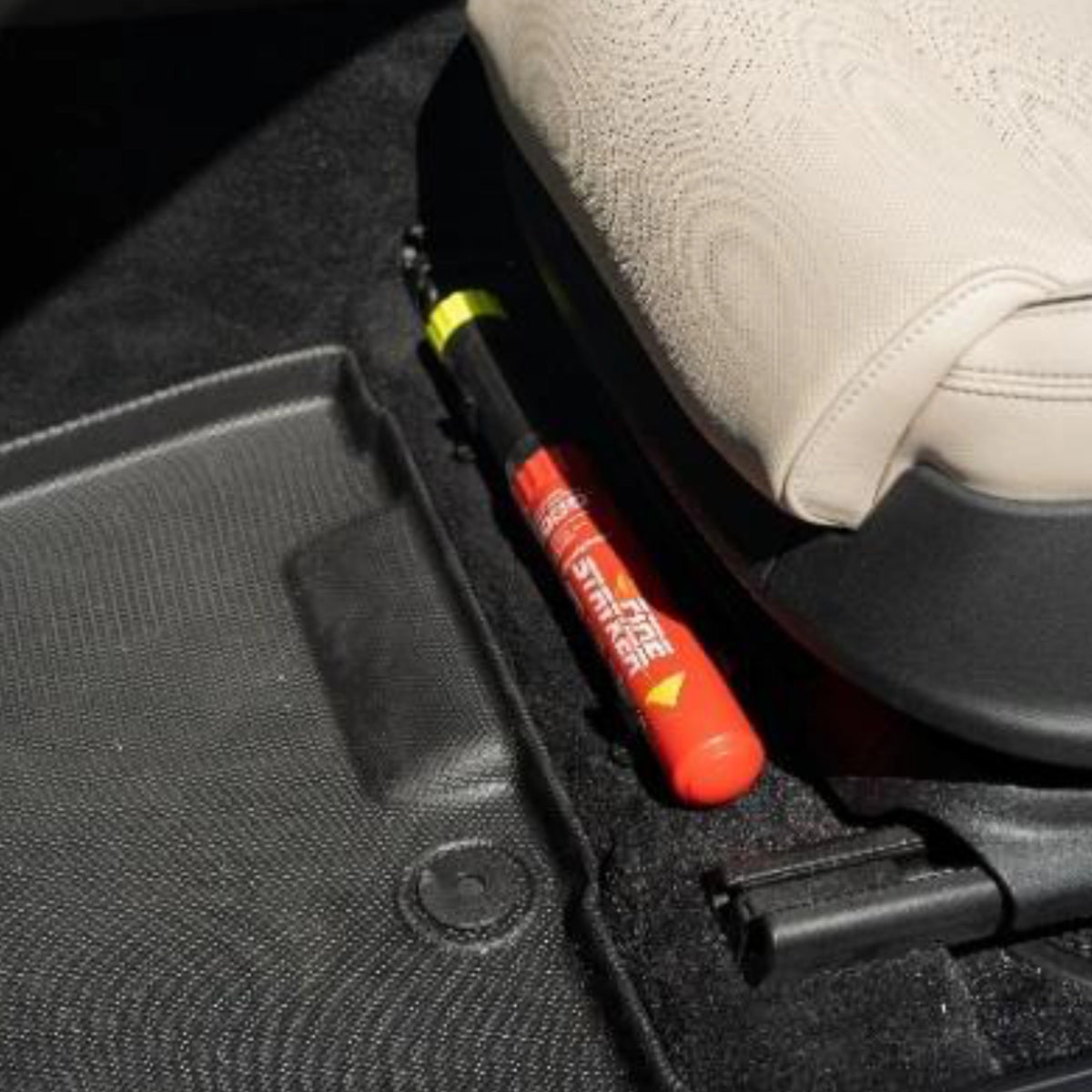 FSS100 fire suppression stick stored between the seat rail and floor mat in a vehicle cabin