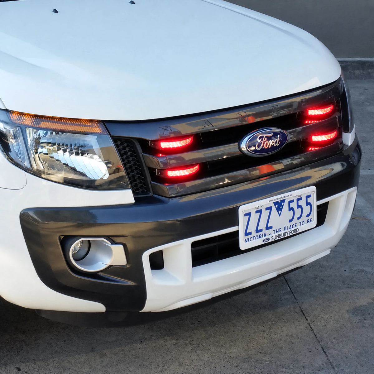 White Ford Ranger ute fitted with four red C9 warning light heads across the front grille, photographed head on