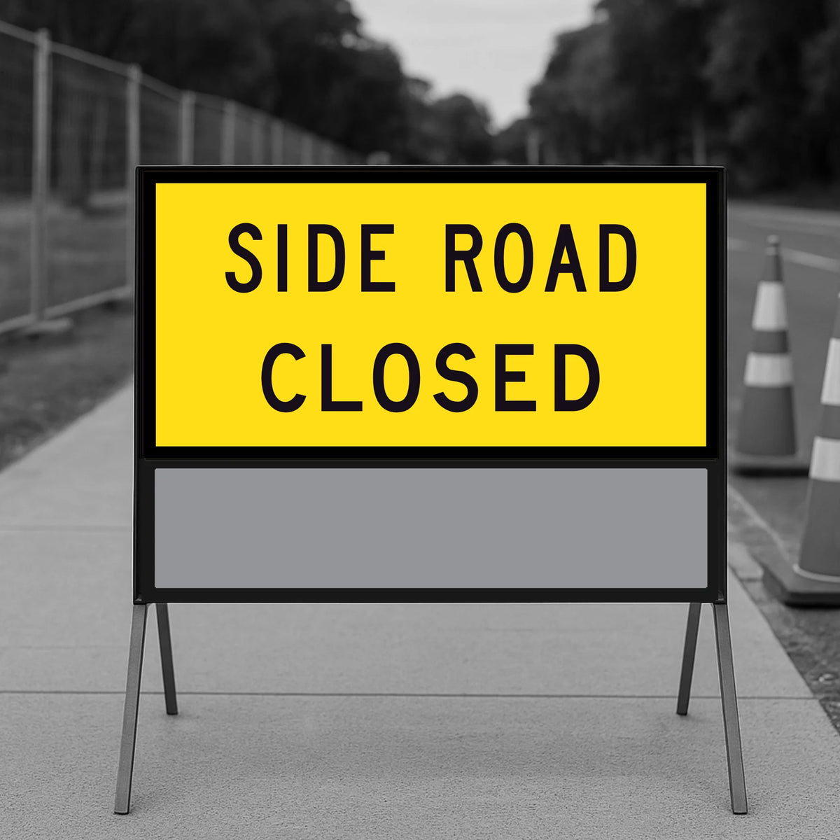 Side Road Closed TM1-32C 1200x600mm corflute panel filling the upper position of a multi-message sign frame with a blank yellow panel below, on a footpath with traffic cones and temporary fencing
