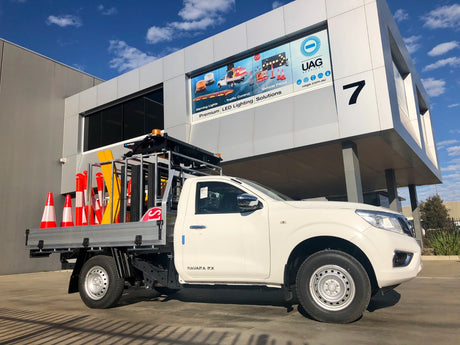 UAG Services warehouse in Bayswater North with a fitted-out Nissan Navara traffic control ute carrying a cage, traffic cones and sign frames