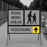 Road work ahead sign with pedestrian symbols and an arrow on a sidewalk.
