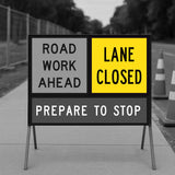 Road work ahead and lane closed sign with traffic cones in the background