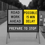 Road work ahead sign with possible delay warning on a road construction site.