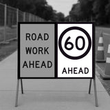 Road work ahead sign with speed limit indication on a stand.