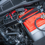 Close-up of a car's battery and electrical system with visible IDC25X connections under bonnet.