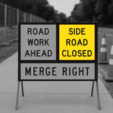 Road work sign indicating 'Road work ahead, side road closed, merge right' on a blurred background.