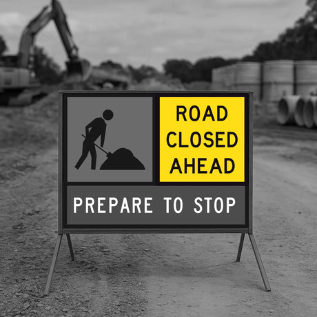 Road closed ahead sign with construction equipment in the background