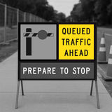 Road sign warning of queued traffic ahead with traffic cones in the background