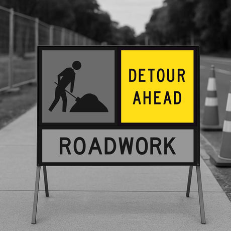 Detour ahead and roadwork sign with construction worker icon on a stand.