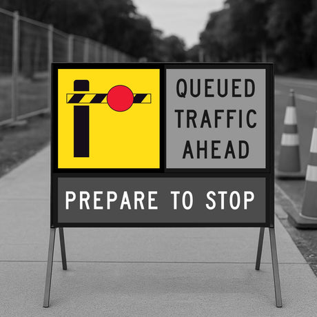 Road sign with boom barrier warning of queued traffic ahead with traffic cones in the background