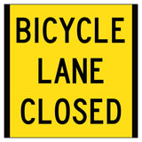 Yellow sign with black text 'BICYCLE LANE CLOSED' on a white background