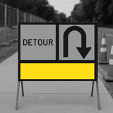 Temporary traffic control detour sign with a U-turn symbol and yellow blank on a road construction site.