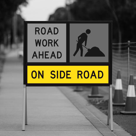 Temporary Traffic Control Road work ahead sign on a sidewalk with traffic cones in the background