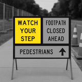 Warning sign on a sidewalk with text 'Watch your step', 'Footpath closed ahead', and 'Pedestrians'.