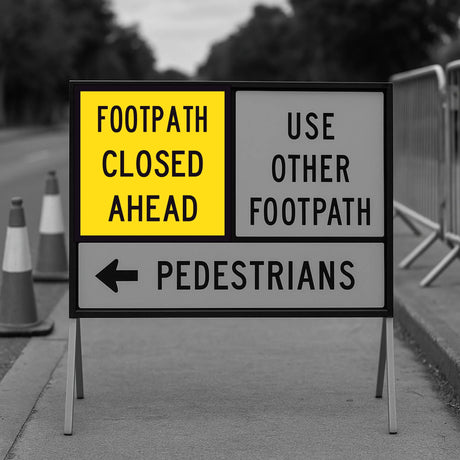 Warning sign indicating a footpath closure with traffic cones and barriers in the background.