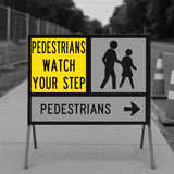 Pedestrian safety sign with text 'PEDESTRIANS WATCH YOUR STEP' and an icon of two people walking on a sidewalk.
