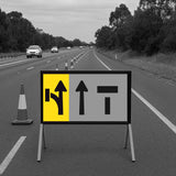 Road sign with traffic direction arrows on a highway with cars in the background