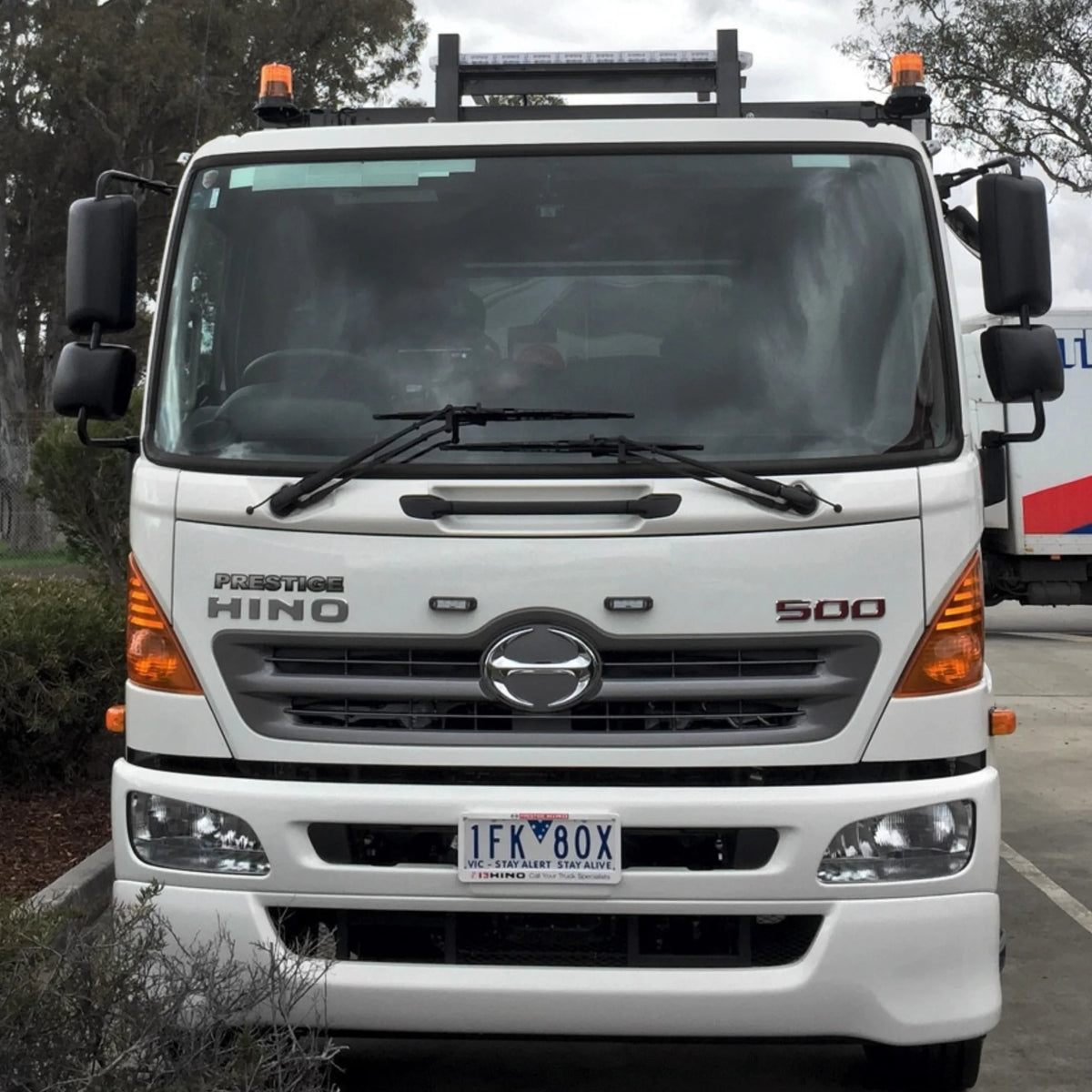 White Hino 500 truck with amber warning lights fitted at the top of the cab, photographed from the front
