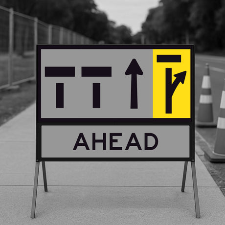 Temporary traffic control lane status road sign with directional arrows and 'AHEAD' text on a stand outdoors.