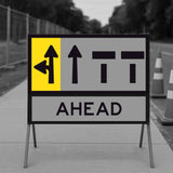 Road sign with directional arrows and 'AHEAD' text on a blurred road background