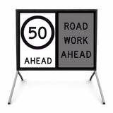 temporary traffic road sign with speed limit 50 ahead and road work ahead warning on a stand.