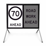 Temporary traffic road sign with speed limit 70 ahead and 'Road Work Ahead' message on a stand.