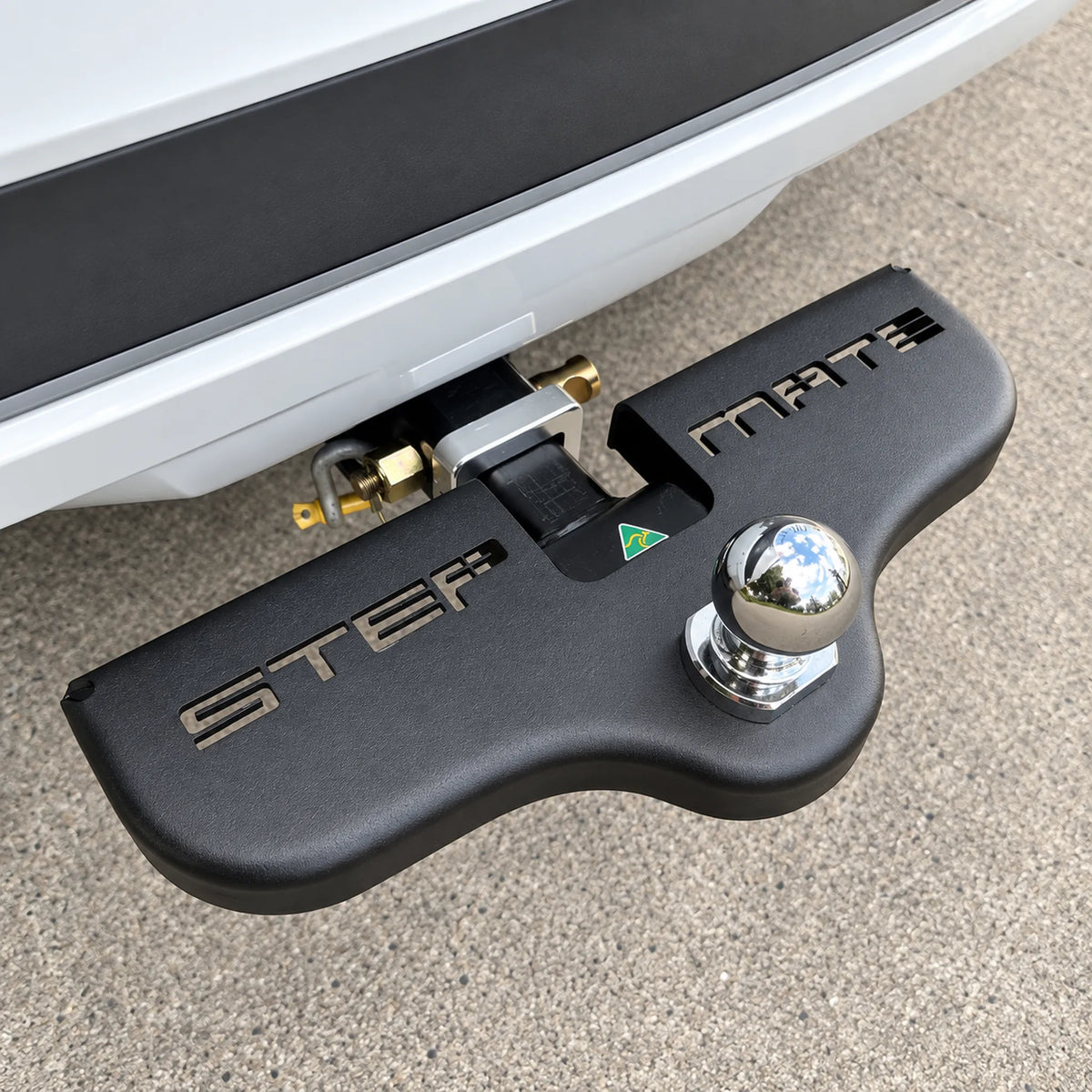 Black Stepmate towbar step fitted under the tow ball on the rear of a white vehicle