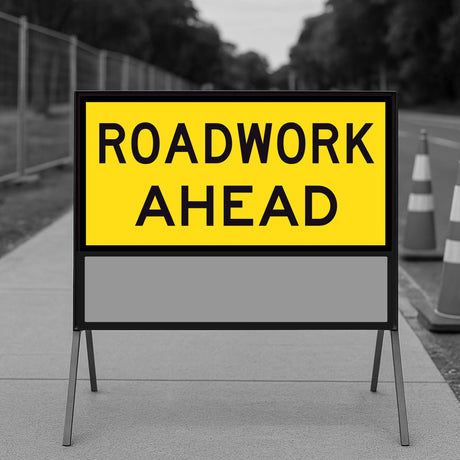 Roadwork Ahead TM1-1C corflute panel mounted in the upper positions of a multi-message sign frame on a roadside, with traffic cones and temporary fencing behind