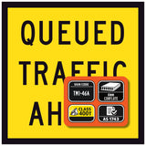 Yellow Queued Traffic Ahead sign with black text and an orange rectangular label on a yellow background