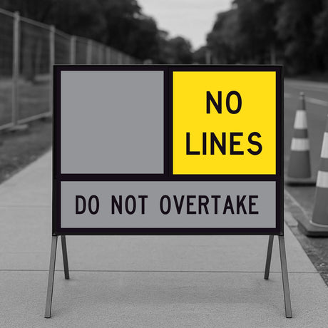 No Lines TM3-17A corflute panel in the top slot of a multi-message sign frame beside a blank yellow panel, with a DO NOT OVERTAKE panel below, on a footpath with traffic cones and temporary fencing