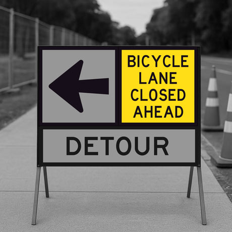 Bicycle Lane Closed Ahead sign panel mounted on a temporary sign frame with a Detour arrow panel and traffic cones in the background