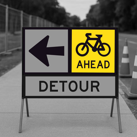 Bicycle Ahead sign panel mounted on a temporary sign frame with a Detour arrow panel and traffic cones in the background