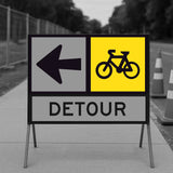 Detour sign with bicycle symbol and left arrow on a road construction site.