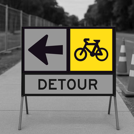 Detour sign with bicycle symbol and left arrow on a road construction site.