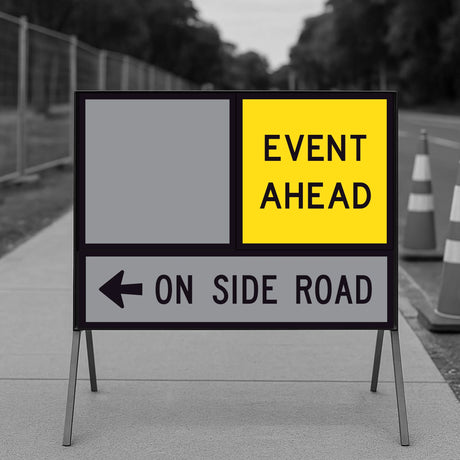 Event Ahead TM9-1A corflute panel in the top slot of a multi-message sign frame beside a blank panel, with an ON SIDE ROAD left arrow panel below, on a footpath with traffic cones and temporary fencing