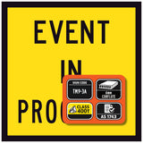 event in progress Yellow sign with black text and an orange rectangular panel containing certification logos.